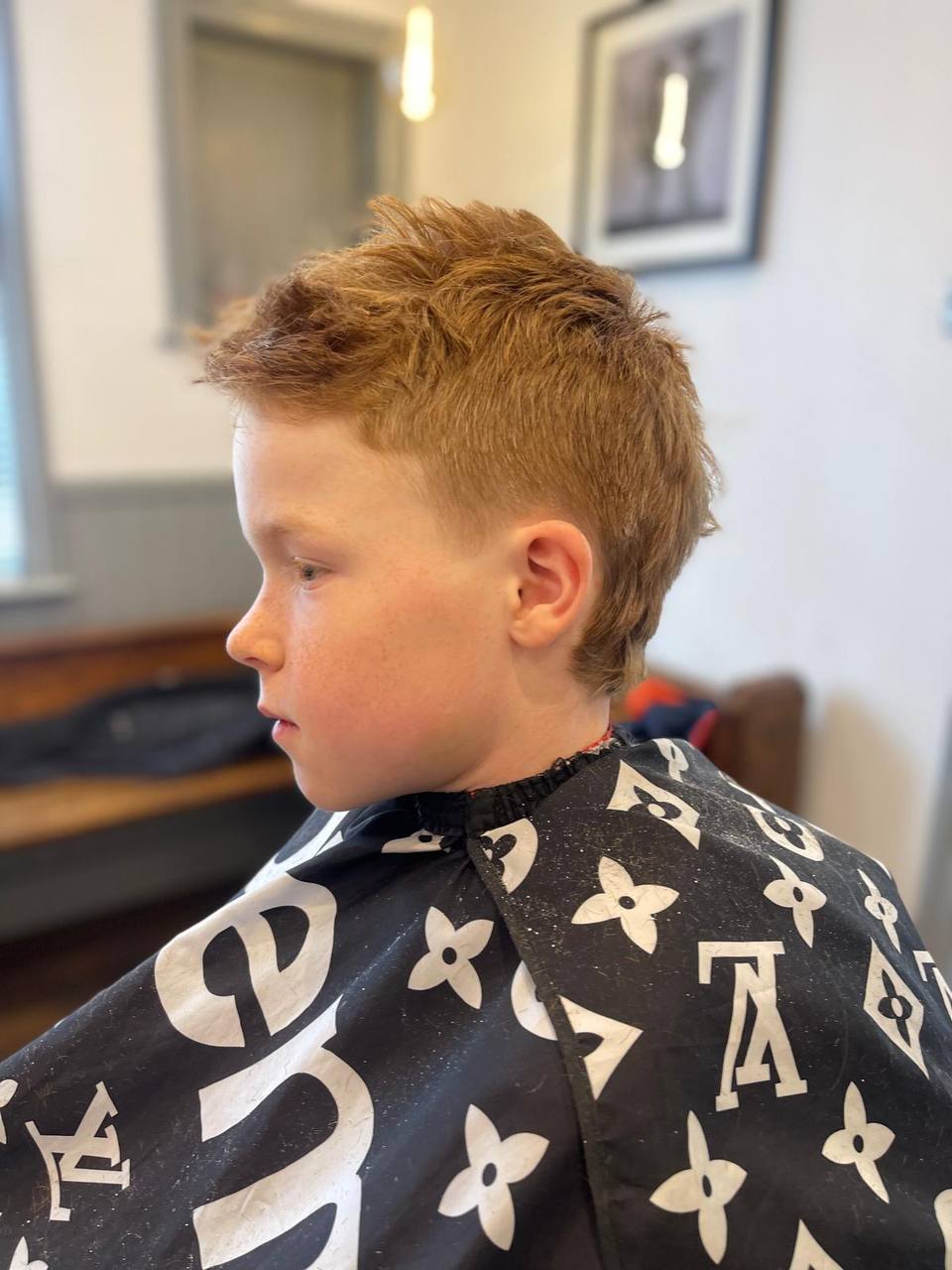 A young boy showing his finished haircut inside the shop